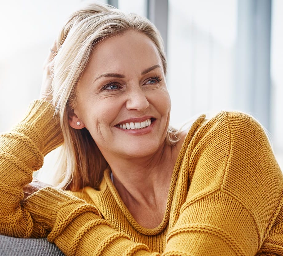 Woman smiling wearing a yellow sweater